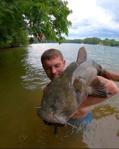 Man in river holding catfish on Lake Norman tour